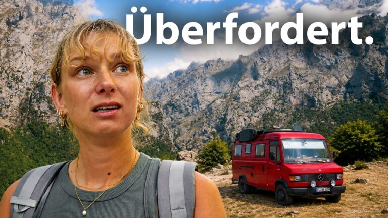 Frau schaut besorgt vor der Kulisse einer felsigen Berglandschaft in Nordspanien mit einem roten Mercedes-Oldtimer-Van im Hintergrund.